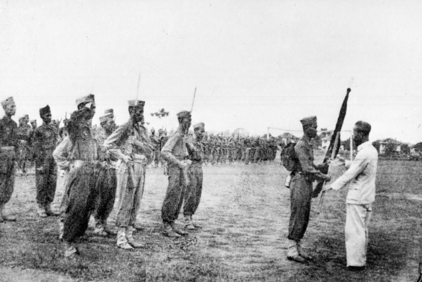 Chủ tịch Hồ Chí Minh trao tặng lá cờ thêu dòng chữ "Trung với Nước, hiếu với Dân" cho các học viên khóa I của Trường Lục quân Trần Quốc Tuấn (22/4/1946). Ảnh: TTXVN